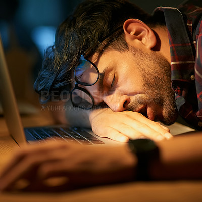 Buy stock photo Cropped shot of a young businessman sleeping on his desk while working late in an office
