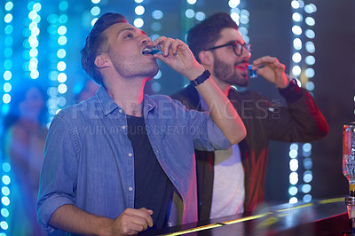 Buy stock photo Shot of two guys drinking shot at the bar counter in a nightclub