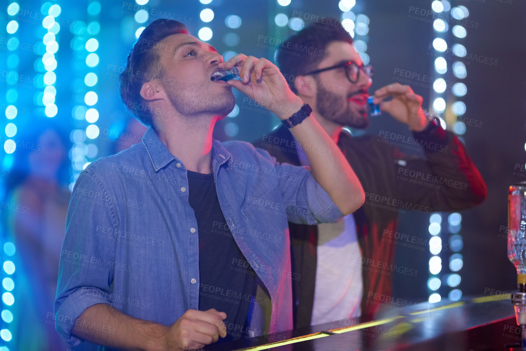 Buy stock photo Shot of two guys drinking shot at the bar counter in a nightclub