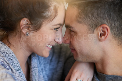 Buy stock photo Shot of an affectionate young couple sitting face to face on the sofa at home