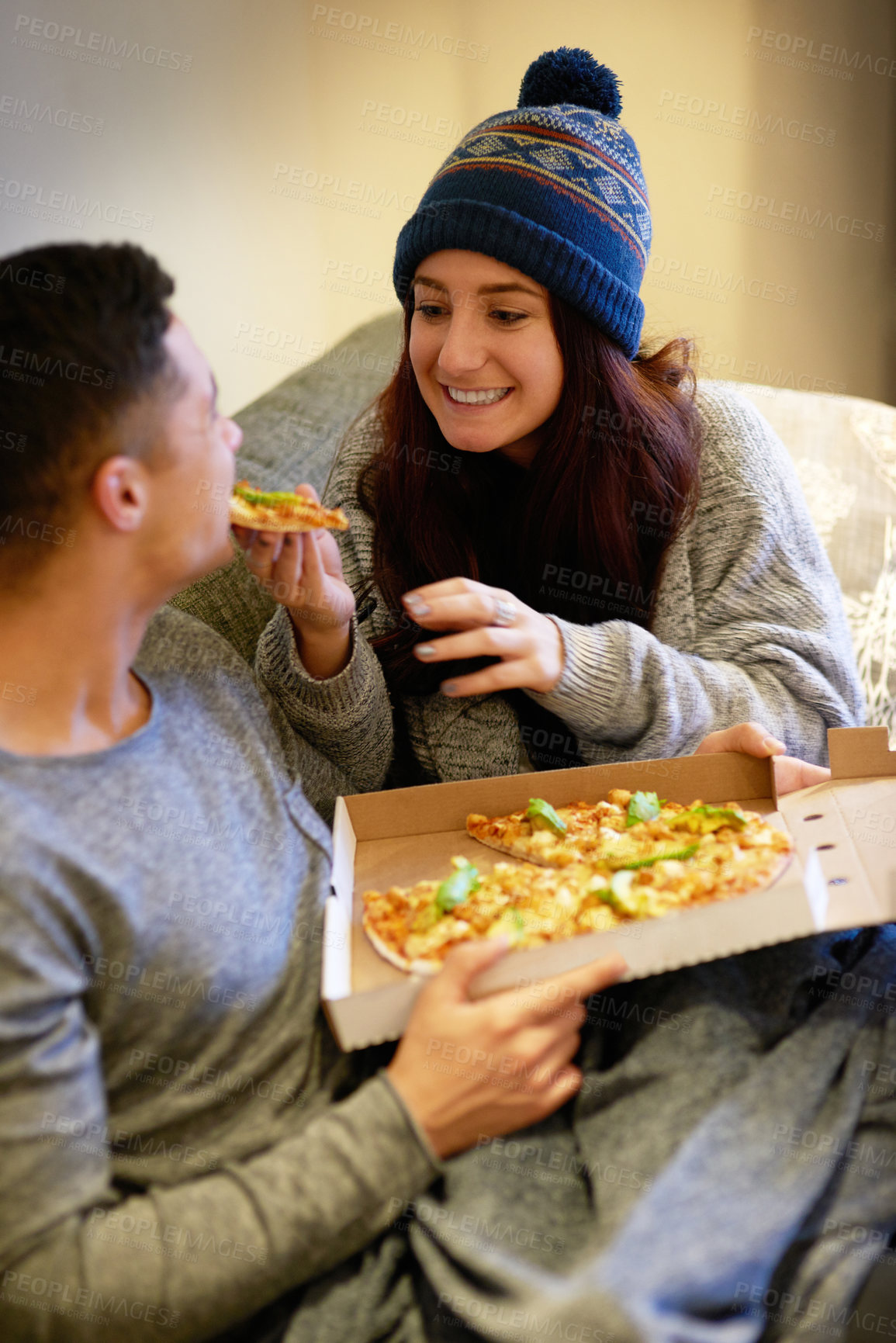 Buy stock photo Shot of a happy young couple eating pizza while relaxing on the sofa at home