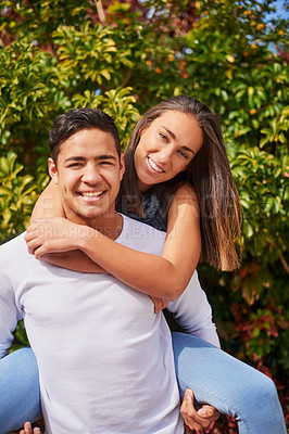 Buy stock photo Portrait of a smiling young man giving his girlfriend a piggyback outside