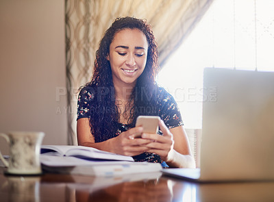 Buy stock photo Shot of a young woman sending a text message while studying