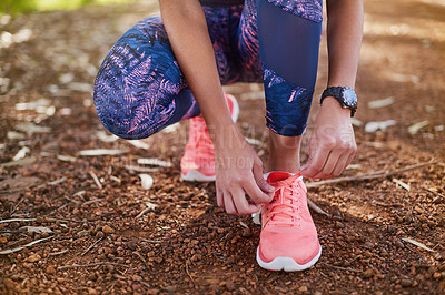 Buy stock photo Cropped shot of a young woman tying her shoelaces before a run
