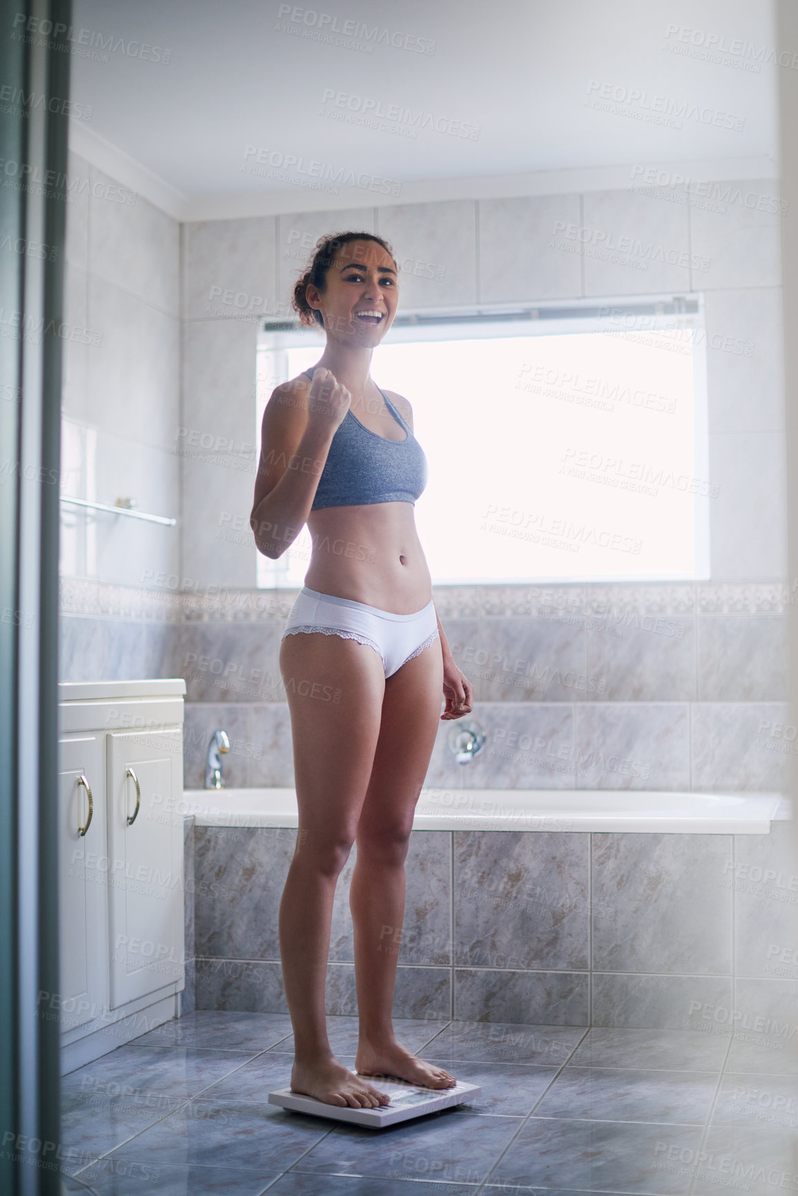 Buy stock photo Weight loss, woman and happy in bathroom on scale with yes, proud and standing in underwear for goals. Female person, success and diet at home for nutrition, fitness and achievement or checking BMI