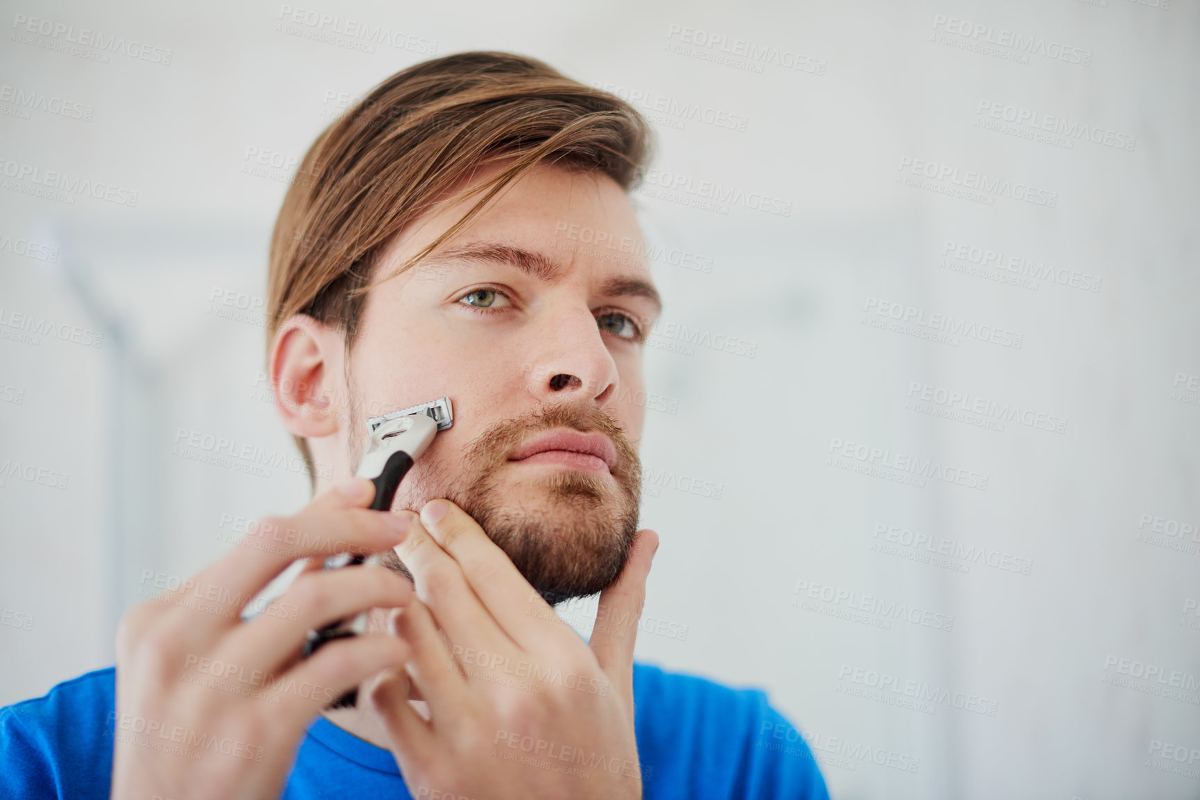 Buy stock photo Cropped shot of a young man shaving his facial hair at home