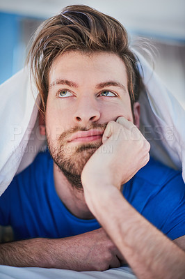 Buy stock photo Cropped shot of a handsome young man looking bored while lying in bed
