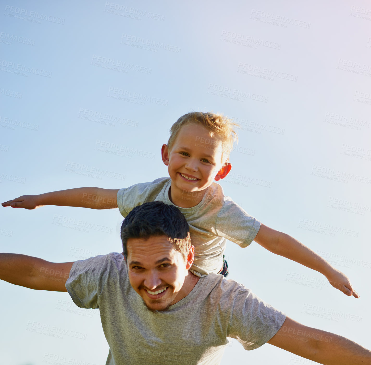 Buy stock photo Shot of a father giving his son a piggyback on a sunny day