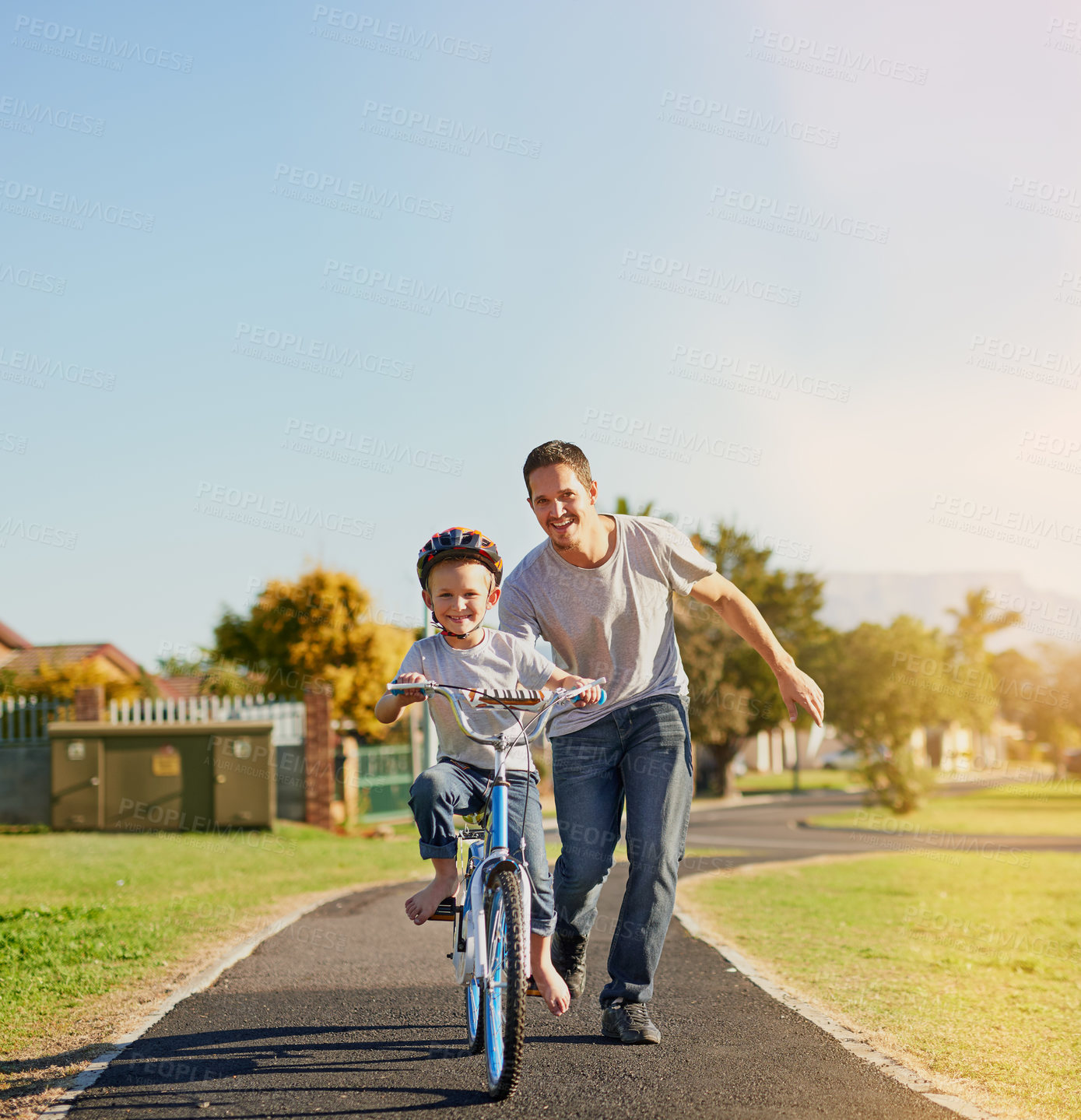 Buy stock photo Shot of a father teaching his little son how to ride a bicycle in the park