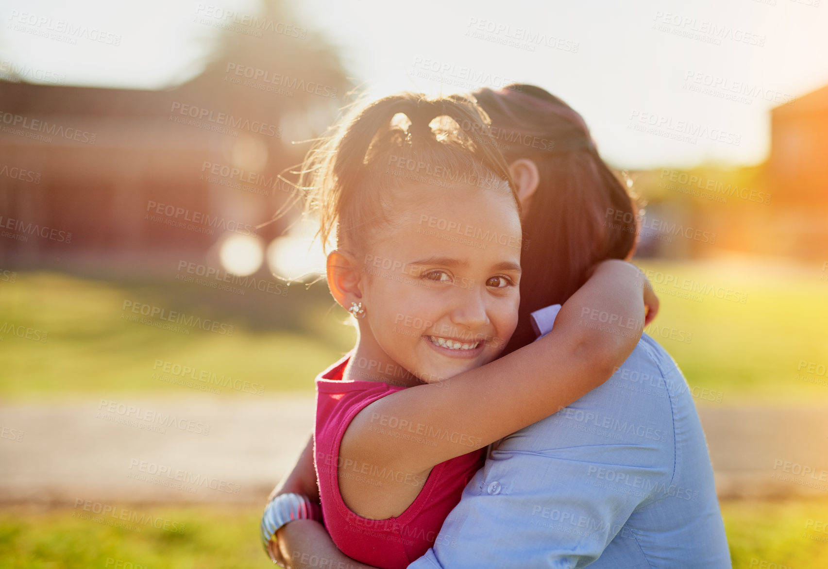 Buy stock photo Portrait of a smiling little girl hugging her mother while enjoying a day together in the park