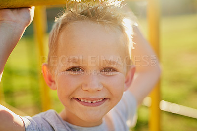Buy stock photo Portrait of a smiling little boy playing on a jungle gym in the park