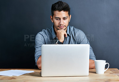 Buy stock photo Cropped shot of a handsome young businessman working on his laptop against a dark background