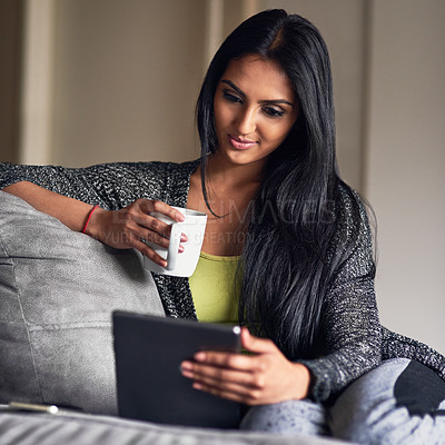 Buy stock photo Shot of an attractive young woman surfing the net while sitting on her sofa at home