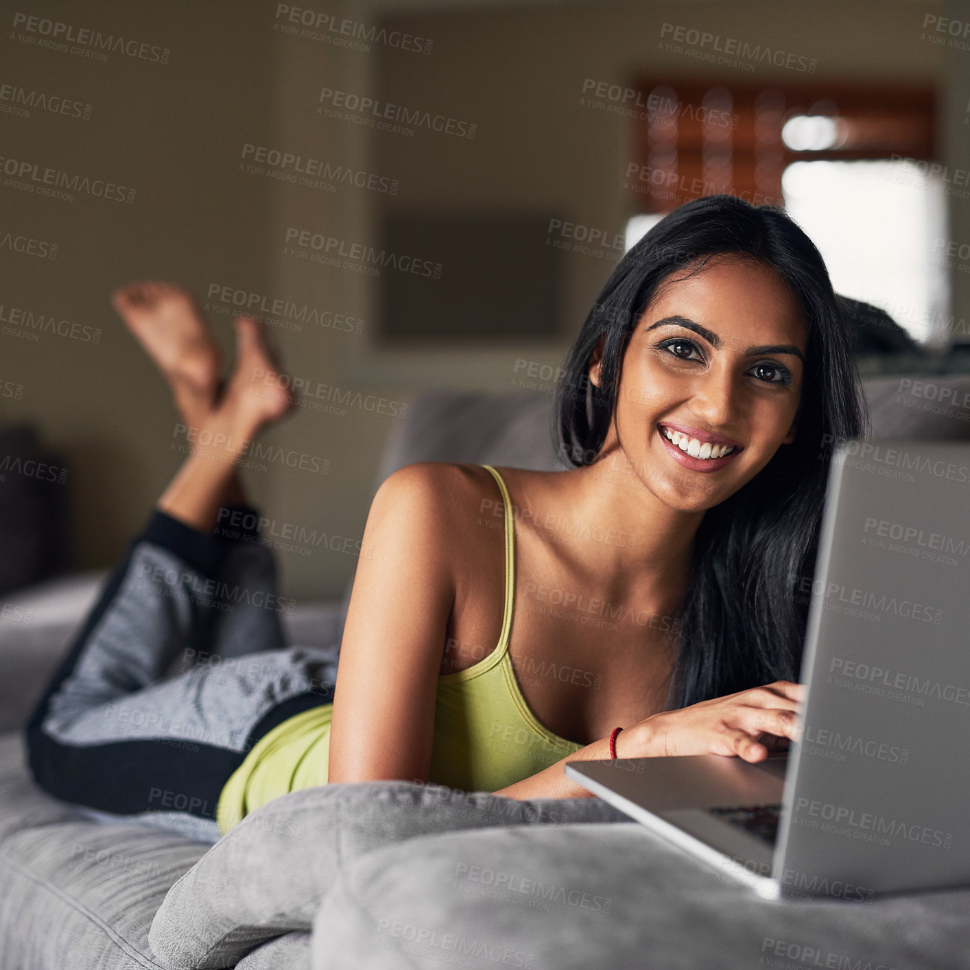 Buy stock photo Portrait of an attractive young woman surfing the net while lying on her sofa at home