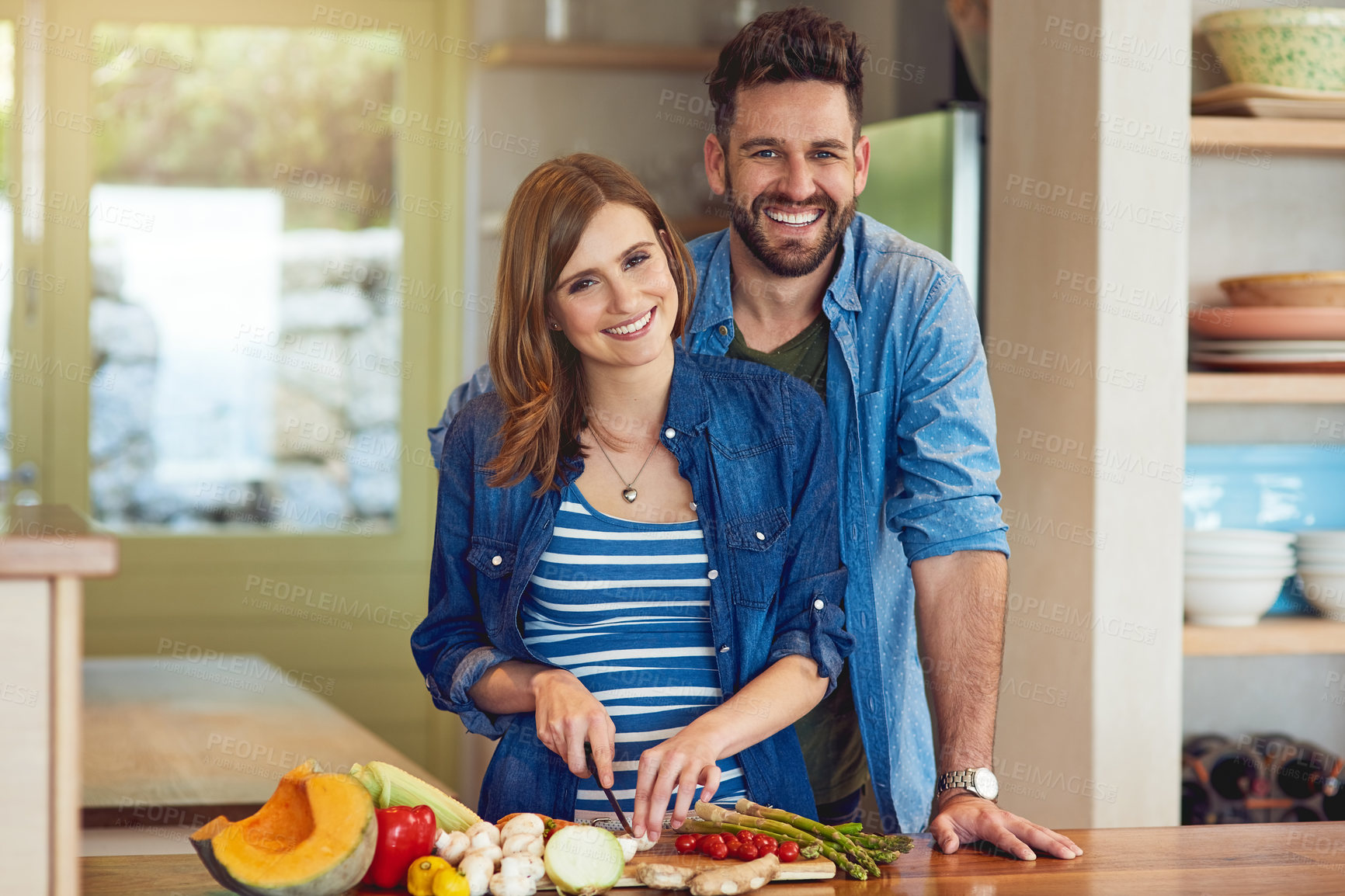 Buy stock photo Portrait of a happy young couple preparing a healthy meal together at home
