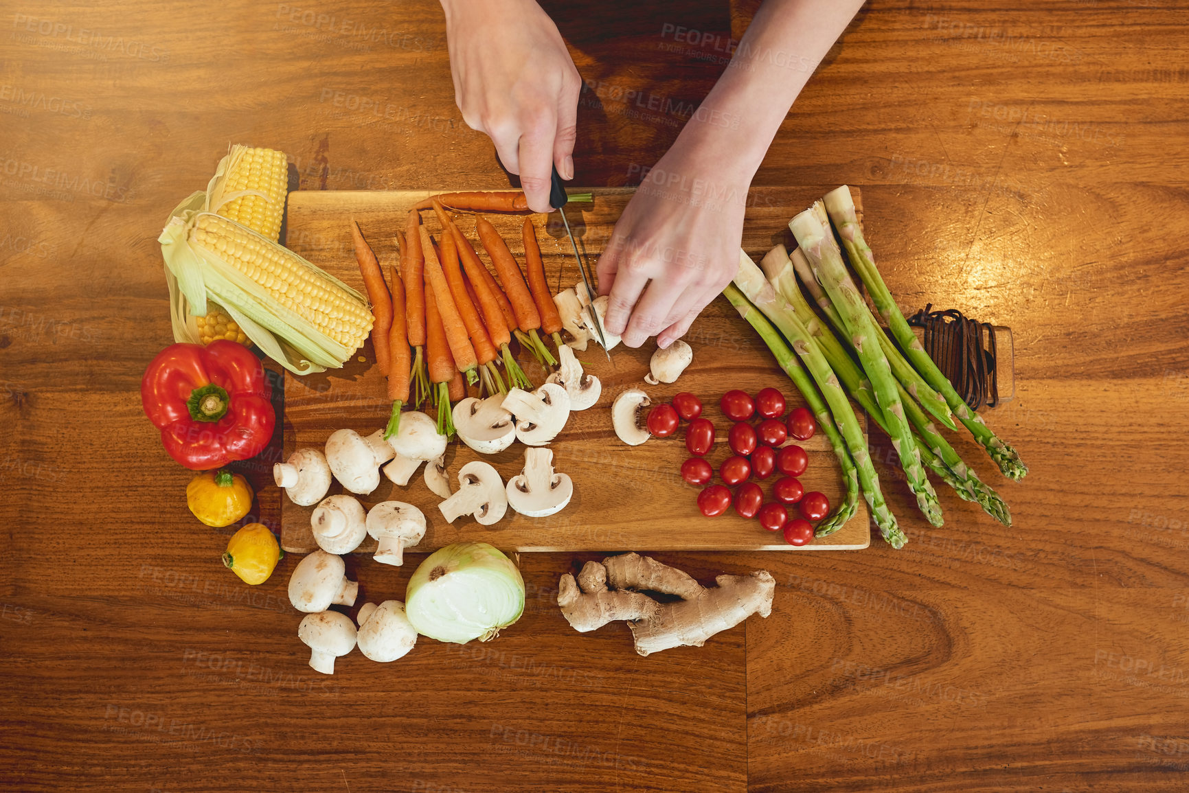 Buy stock photo High angle shot of a woman cutting a variety of healthy vegetables on a chopping board