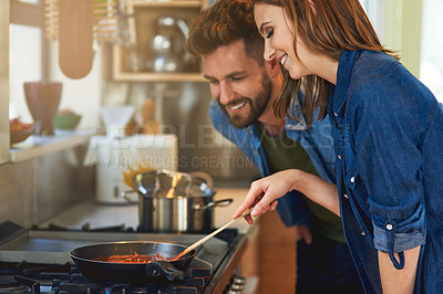 Buy stock photo Shot of a happy young couple cooking a meal together on the stove at home
