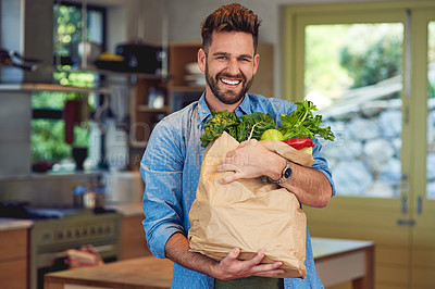 Buy stock photo Portrait of a happy man holding a bag full of healthy vegetables at home