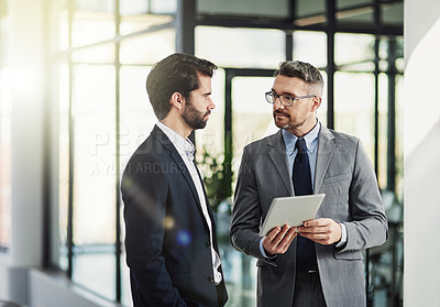 Buy stock photo Shot of two businessmen looking over a tablet in the office