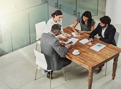 Buy stock photo Shot of a group of colleagues sitting around a meeting tablet in the office