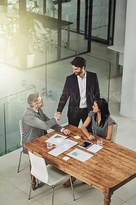 Buy stock photo Shot of two businessmen shaking hands during a meeting in the office