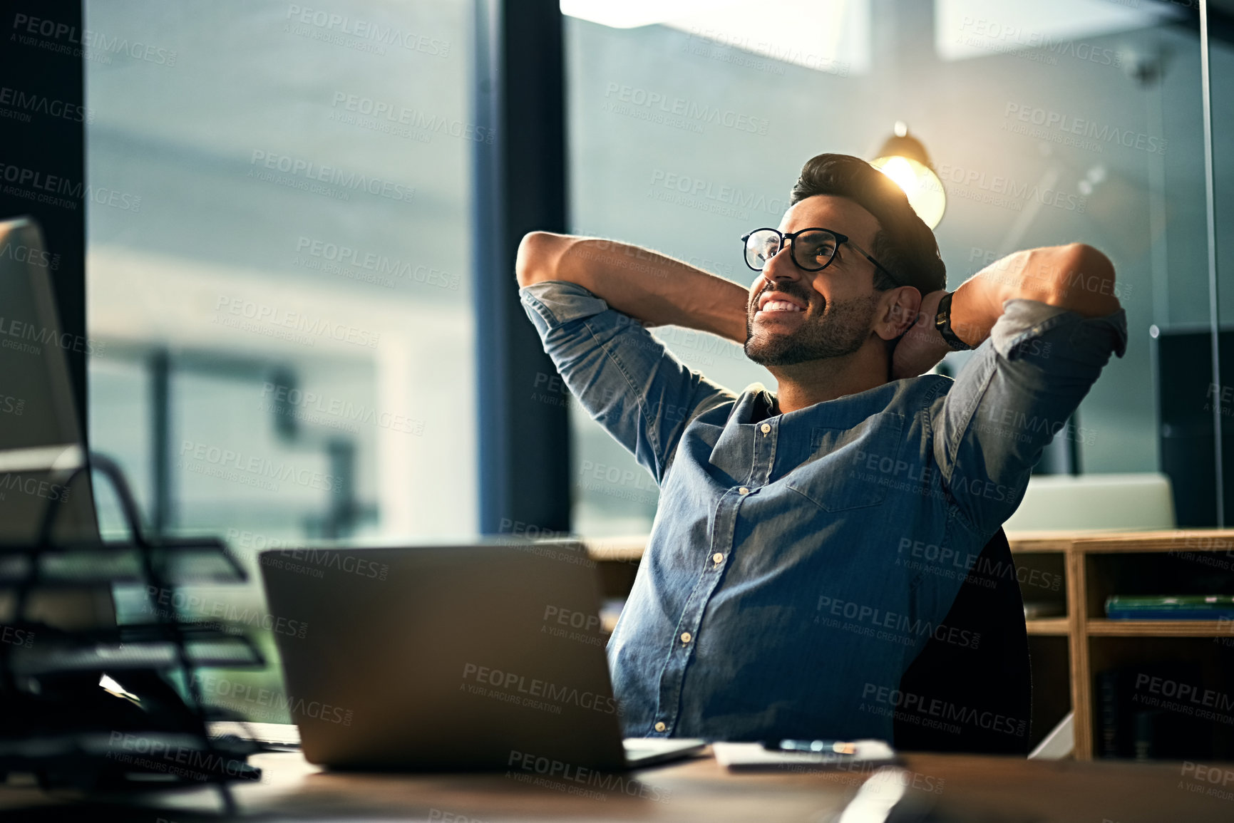 Buy stock photo Shot of a young businessman taking a break at his desk during a late night at work