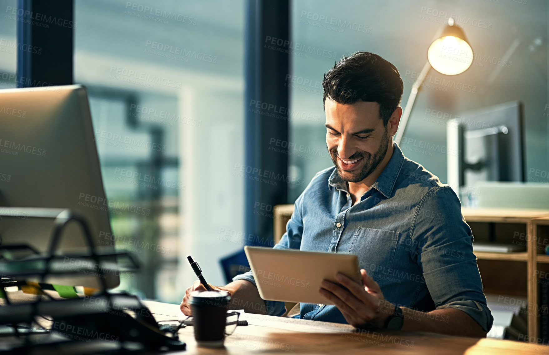 Buy stock photo Shot of a young businessman using a digital tablet during a late night at work