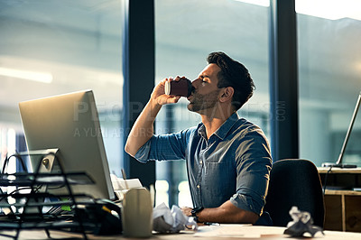 Buy stock photo Shot of a young businessman drinking coffee during a late night at work