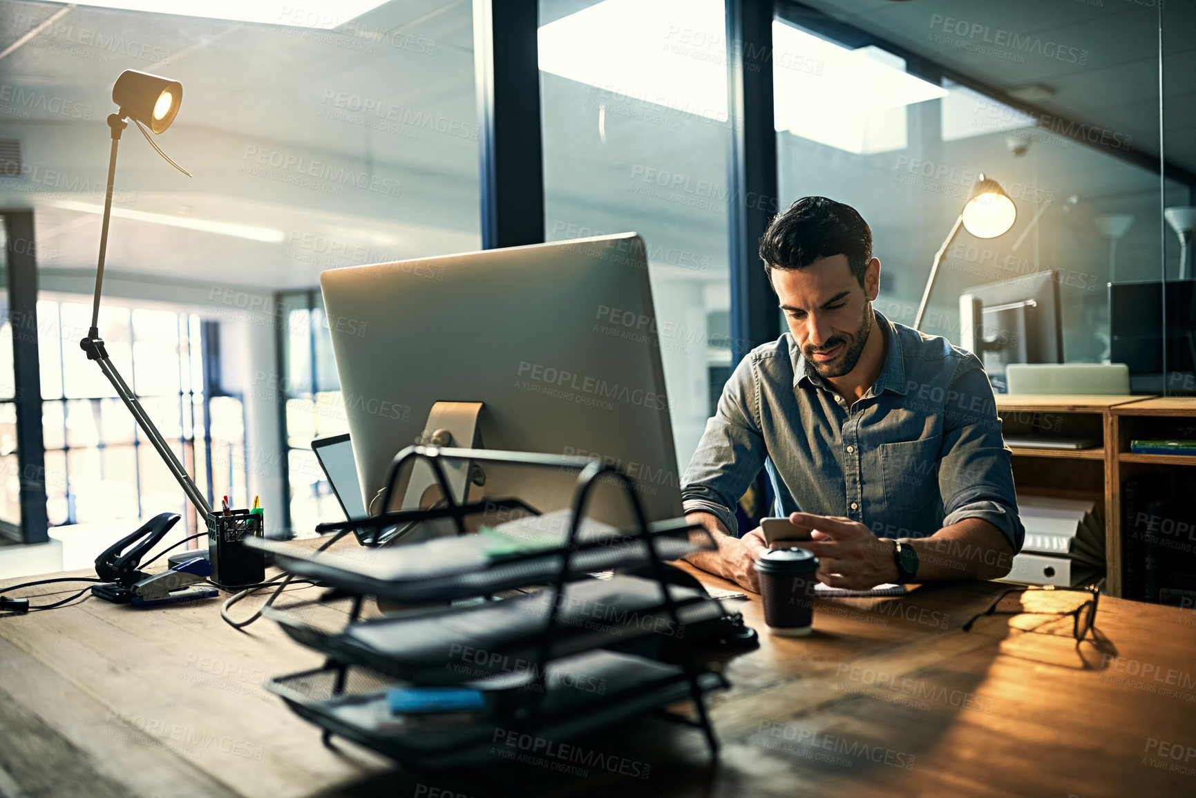 Buy stock photo Shot of a young businessman using a phone during a late night at work