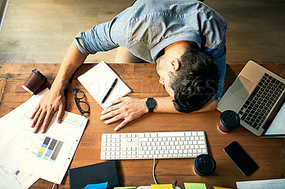 Buy stock photo Shot of an exhausted young businessman sleeping at his desk during a late night at work
