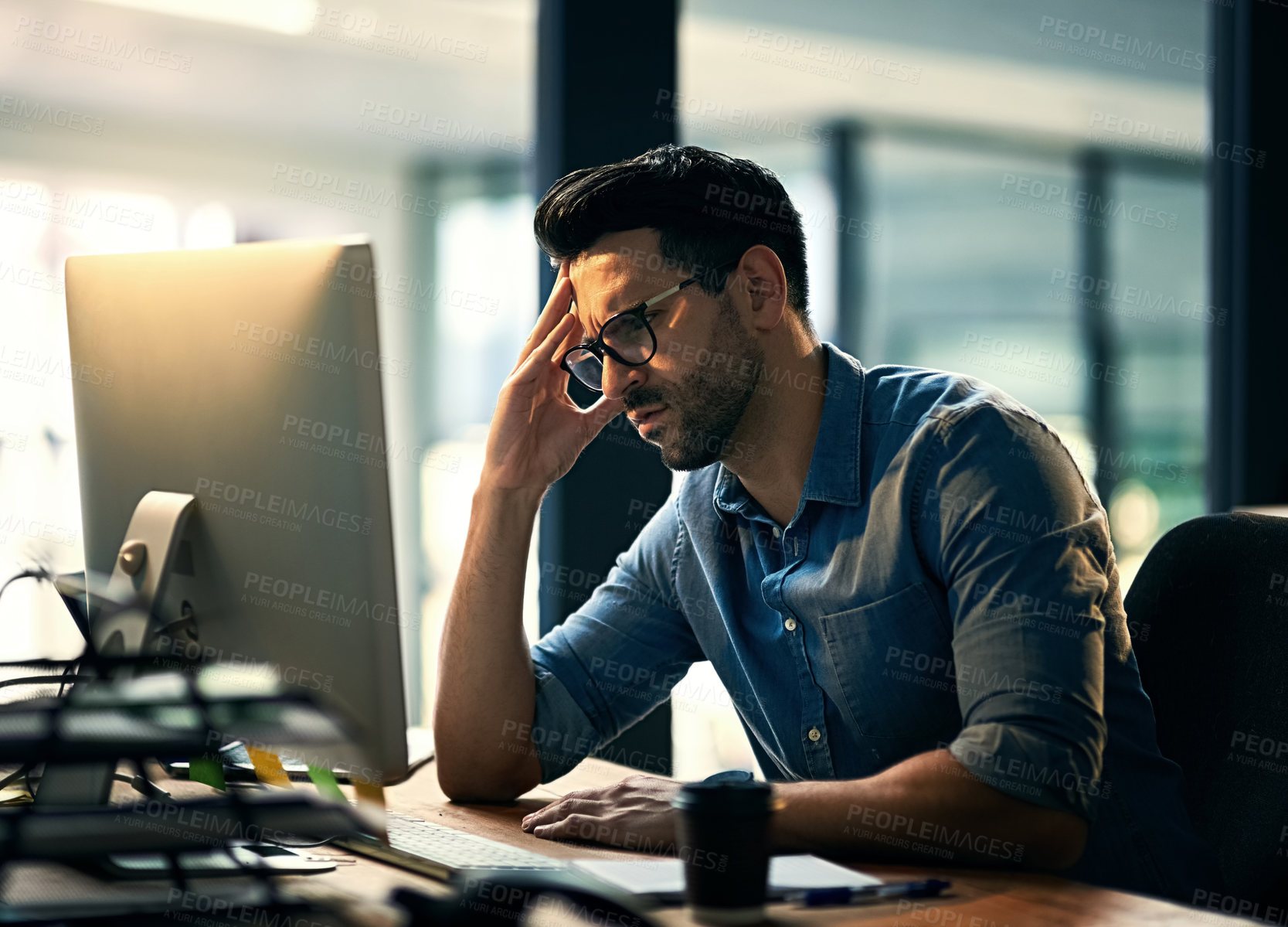 Buy stock photo Shot of a young businessman experiencing stress during a late night at work