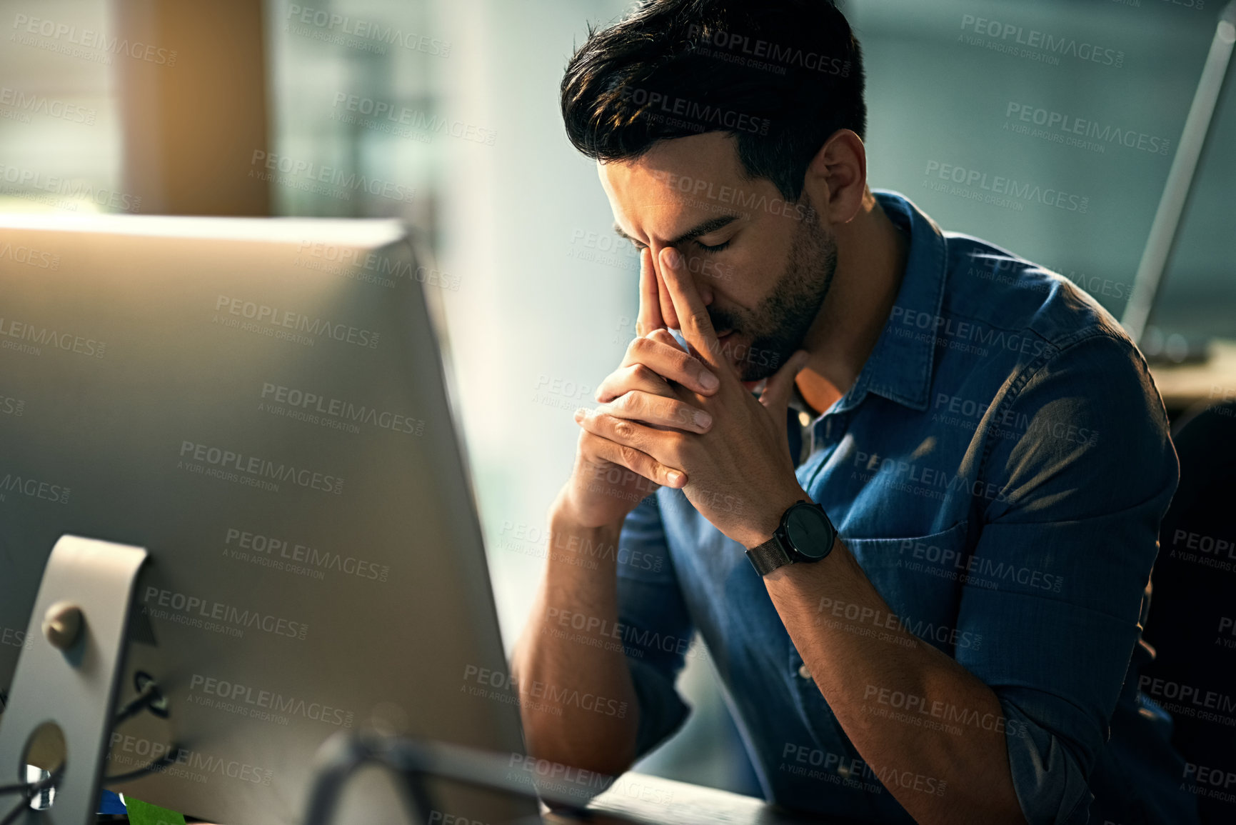 Buy stock photo Shot of a young businessman experiencing stress during a late night at work