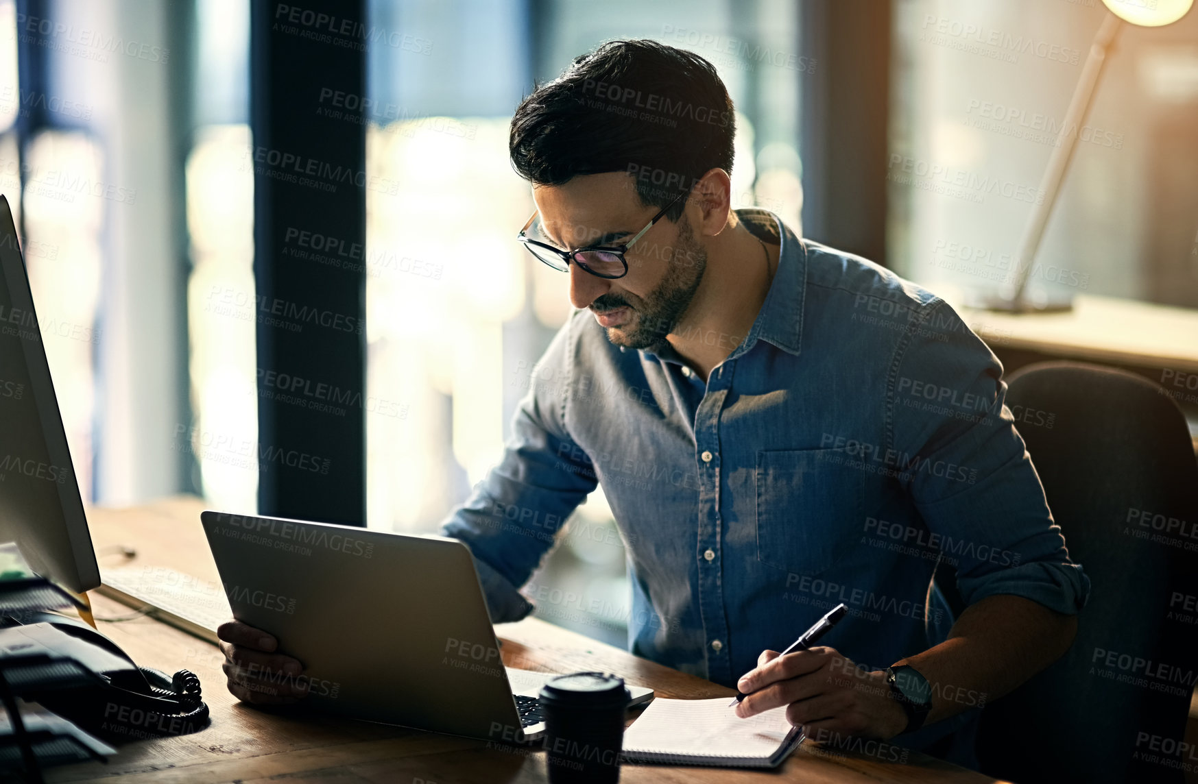 Buy stock photo Shot of a young businessman using a laptop during a late night at work