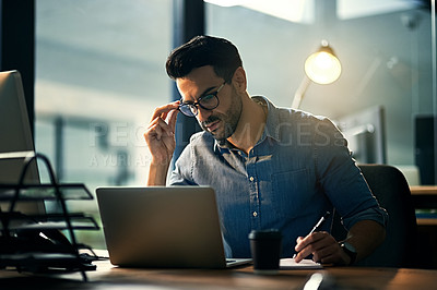 Buy stock photo Shot of a young businessman using a laptop during a late night at work
