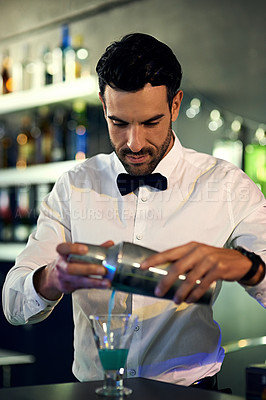 Buy stock photo Shot of a barman mixing drinks behind the bar in a nightclub