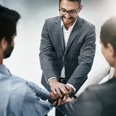 Buy stock photo High angle shot of three businesspeople standing with their hands in a huddle