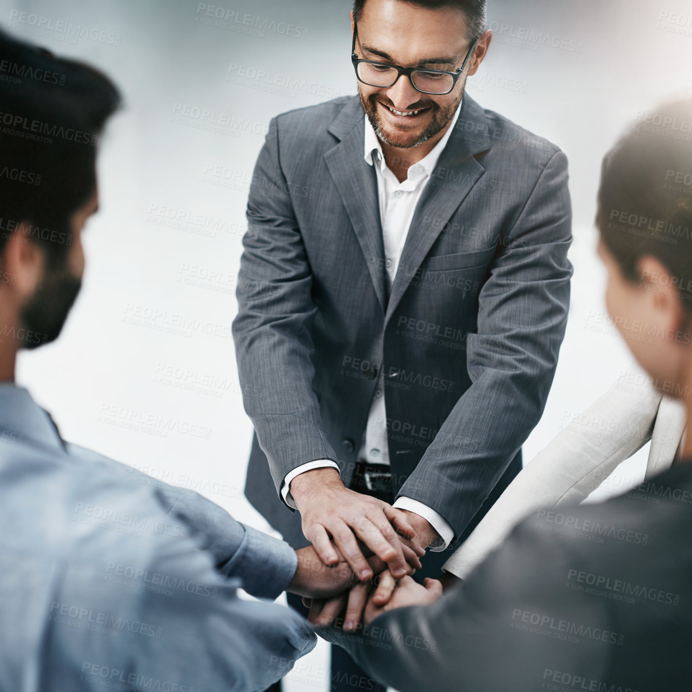 Buy stock photo High angle shot of three businesspeople standing with their hands in a huddle