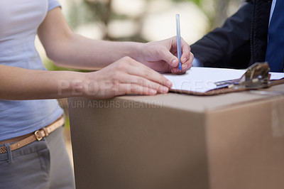 Buy stock photo Shot of an unidentifiable woman signing for the delivery of a package