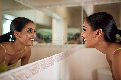 Buy stock photo Cropped shot of a young woman looking at her face in the bathroom mirror