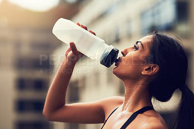 Buy stock photo Cropped shot of a sporty young woman drinking water after her run