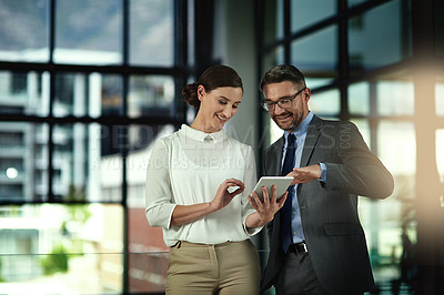Buy stock photo Shot of two businesspeople looking over a tablet in the office