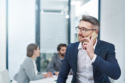 Buy stock photo Shot of a handsome businessman taking a call during a meeting in the boardroom