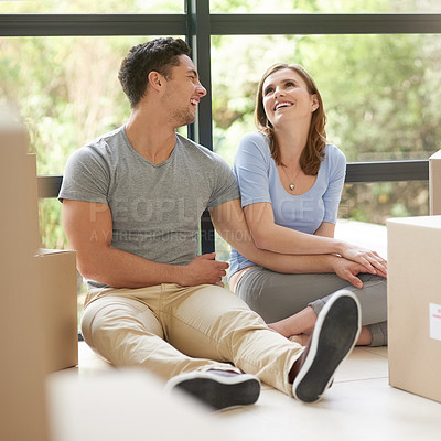 Buy stock photo Shot of a happy young couple relaxing in their new home while moving in