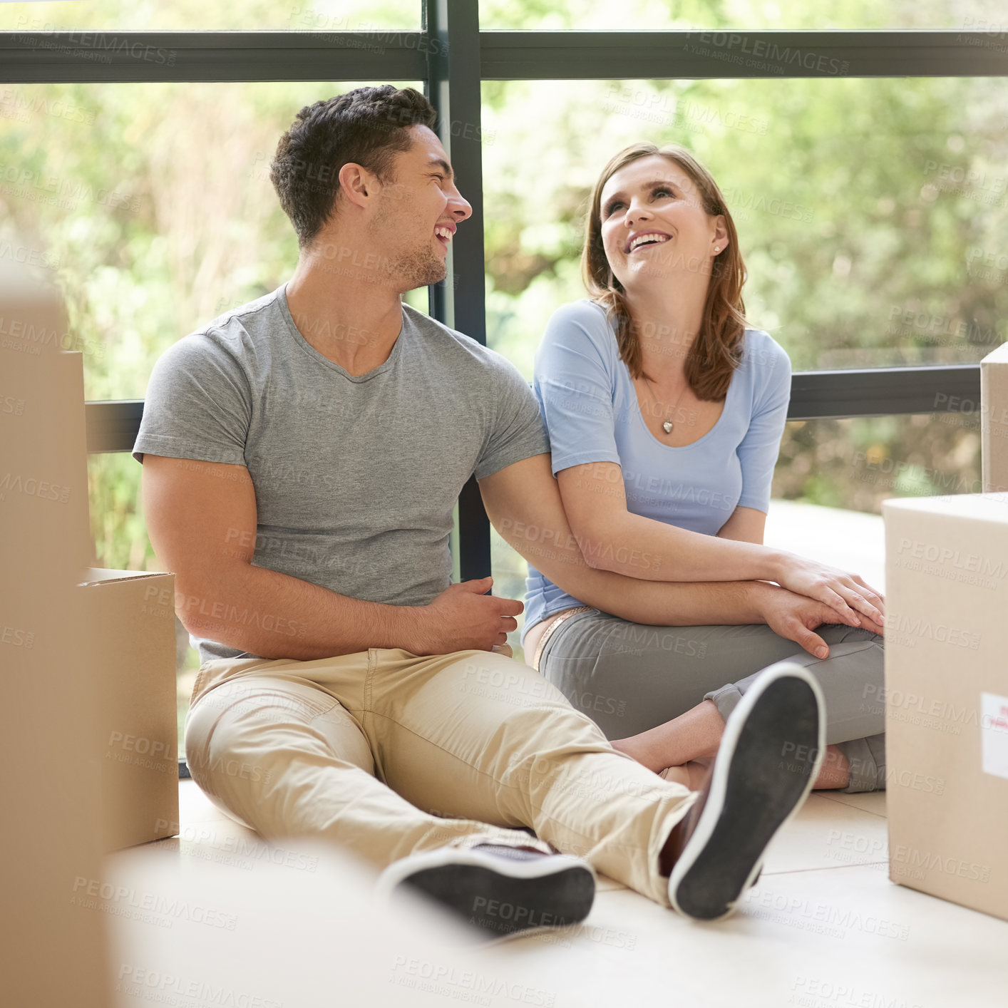 Buy stock photo Shot of a happy young couple relaxing in their new home while moving in