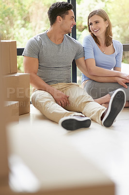 Buy stock photo Shot of a happy young couple relaxing in their new home while moving in