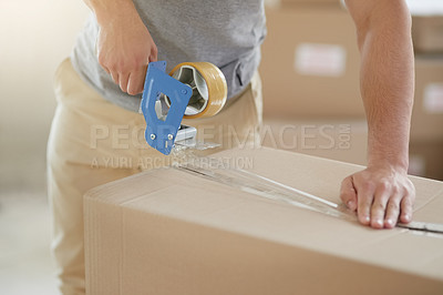 Buy stock photo Shot of an unidentifiable young man closing a cardboard box with tape at home