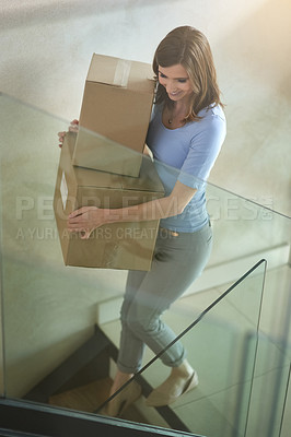 Buy stock photo Shot of a happy young woman carrying boxes while moving out of her house