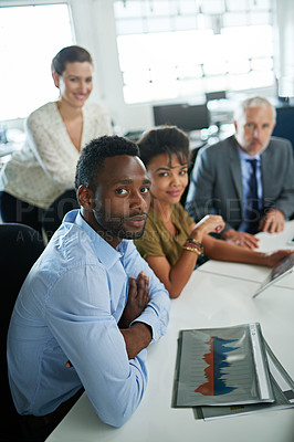 Buy stock photo Portrait of a group of focused coworkers sitting at a desk in an office