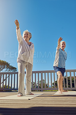 Buy stock photo Shot of a senior couple doing yoga together on their patio outside
