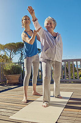 Buy stock photo Shot of a senior woman doing yoga with an instructor on a patio outside